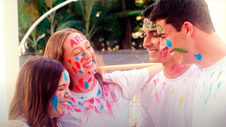Grupo de jovens comemorando a aprovação no vestibular, com tintas no rosto, em celebração. Thumbnail do video institucional Poliedro Curso.